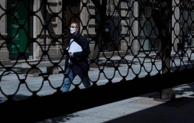 Un hombre camina por una calle por delante de la persiana semibajada de un comercio en los meses más duros de la pandemia.
