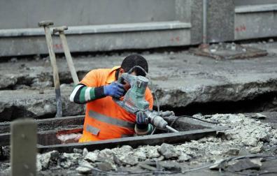 Un trabajador realiza obras en el asfalto de una calle.