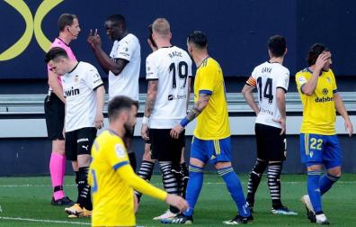 El defensa del Valencia Mouctar Diackhaby conversa con el árbitro Medié Jiménez momentos antes de abandonar el terreno de juego por un insulto racista de Juan Cala