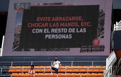 Dos aficionados en Mestalla con un mensaje a sus espaldas.