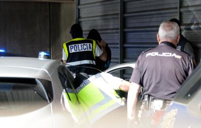 Agente lleva a uno de los acusados para declarar como presunto autor de la paliza