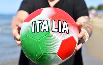 Un aficionado sujeta yun balón con los colores de Italia en la playa de Castiglione della Pescaia
