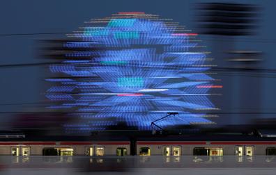 Un tren pasa ante la gran noria iluminada de Tokio instalada con motivo de la celebración de los Juegos Olímpicos