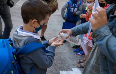 Una profesora vierte gel hidroalcohólico en las manos de un alumno del CP Paderborn (Pamplona), el primer día de clase del curso pasado.	Garzaron