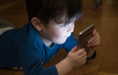 Imagen de archivo de un niño usando un teléfono móvil.
