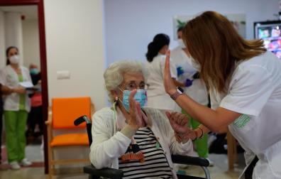 Una anciana de una residencia de ancianos celebra con una enfermera la tercera dosis de la vacuna contra el coronavirus
