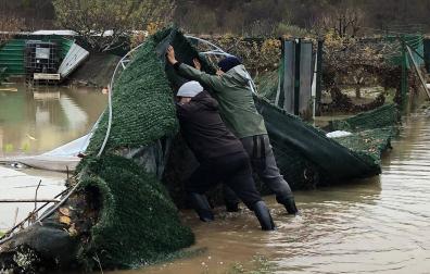 Josetxo Garralda Guerrero, con gorro gris, ayuda a su padre a levantar una parte de la valla arrastrada por el río Arga a su paso por las huertas de Zokoa en Huarte