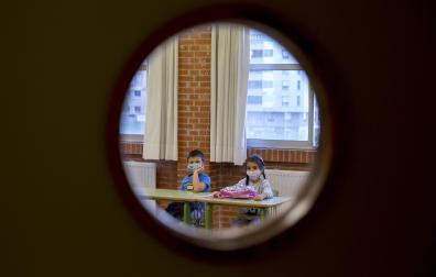 Dos menores, con el rostro cubierto con una mascarilla, aguardan al inicio de una clase en el C.P. Azpilagaña en el arranque de un curso