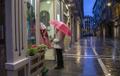 Una mujer observa un escaparate ayer tarde en la calle Mayor, en medio de la lluvia