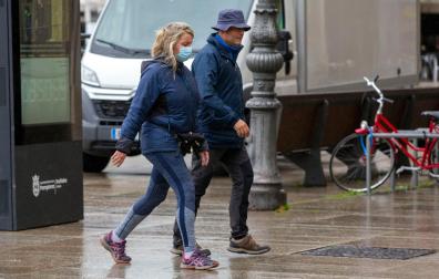Dos personas por una calle de Pamplona, una de ellas con mascarilla y la otra no