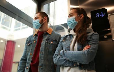 Dos personas con mascarilla en un ascensor