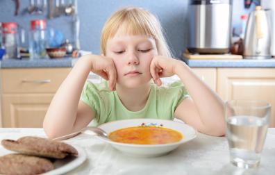 Una niña, frente a un plato de comida