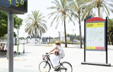 Una mujer pasea en bicicleta en Sevilla bajo un termómetro que marca 45 grados