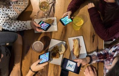 Un grupo de amigas consulta su móvil paga pagar la cuenta en un bar de Pamplona