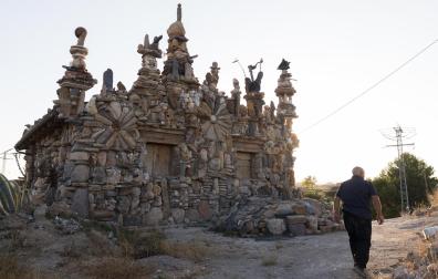 Armando Baigorri, de espaldas, junto a la casa que ha ido recubriendo con más de un millón de piedras en Monteagudo.