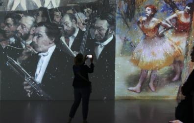 Pantallas gigantes proyectan imágenes en movimiento de las obras, como estas de Degas