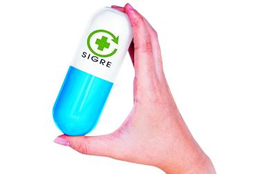 Una mano sujeta una cápsula con forma de medicamento con el logotipo del Sigre