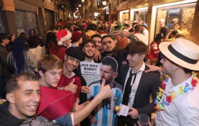 Mikel Aceldegui, con camisa y corbata, junto con su cartel de Messi en la calle San Nicolás, uno de los lugares más concurrido de la noche
