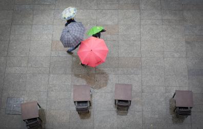 Varias personas se protegen ayer de la lluvia con sus paraguas en Pamplona.