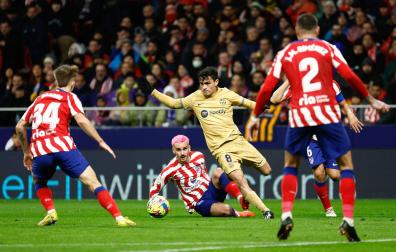 El centrocampista del FC Barcelona, Pedri, se lleva el balón ante el delantero francés del Atlético de Madrid, Antoine Griezmann