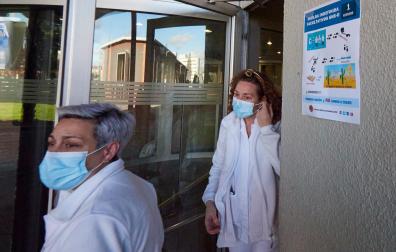 Dos profesionales junto a la puerta de acceso del Hospital Universitario de Navarra donde había un cartel informativo sobre la huelga