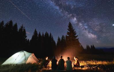 Unos jóvenes contemplan el cielo estrellado durante una acampada