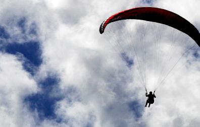 Un practicante de parapente se abalanza sobre un mar de nubes bajas