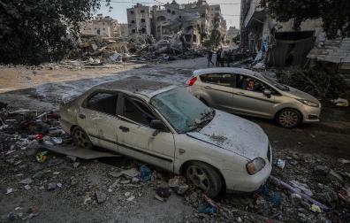 Un niño palestino mira un coche destruido por los bombardeos aéreos israelíes