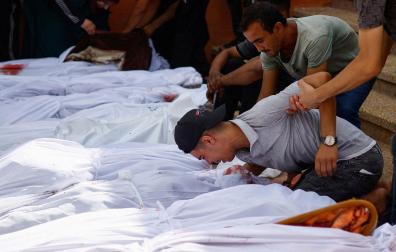 Un familiar de uno de los cientos de fallecidos en el ataque a un hospital de Gaza se despide con un beso en medio de otros cadáveres