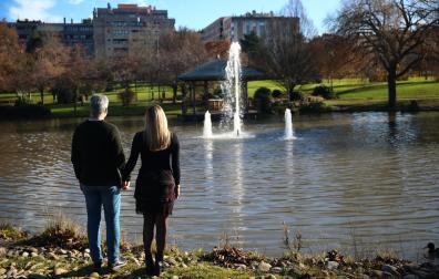 Con las manos entrelazadas, la pareja comprometida contempla el estanque del parque Yamaguchi. A la derecha, la publicación.