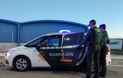 Imagen de dos agentes de la Guardia Civil junto a un coche patrulla