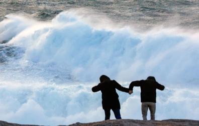 Dos turistas observan el oleaje en la cosa de Muxía, este miércoles en A Coruña