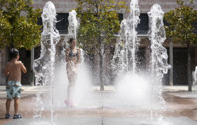 Una niña pasa entre los chorros de agua de la fuente de Yamaguchi, en Pamplona