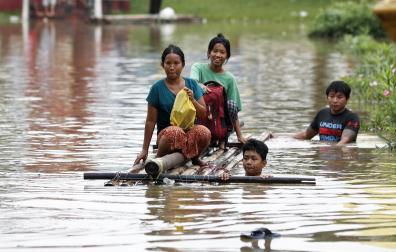 Varias personas se mueven en una balsa por las calles de la localidad de Taungoo en Birmania tras la fuertes lluvias registradas