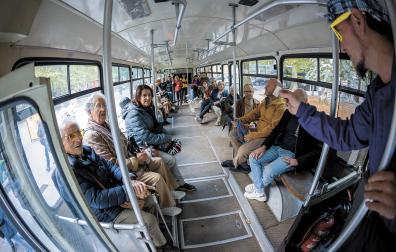 El actor en el papel de conductor muestra un antiguo billete ante los visitantes a la villavesa del Bosquecillo