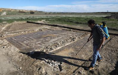 Alex Duró mojando los dos mosaicos descubiertos por completo en Campo de Arlas, el yacimiento arqueológico de Peralta