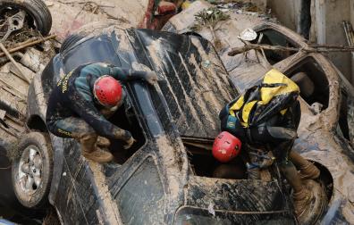 Expertos de la Guardia Civil buscan cuerpos sin vida entre los vehículos atrapados entre los cimientos de un edificio en construcción, este sábado en Paiporta