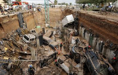Expertos de la Guardia Civil buscan cuerpos sin vida entre los vehículos atrapados entre los cimientos de un edificio en construcción, este sábado, en Paiporta
