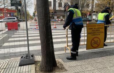 Dos agentes de Policía Municipal colocan cintas para evitar que peatones se cuelen por el paso de cebra anulado en Pío XII