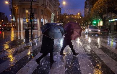 Dos personas se protegen de la intensa lluvia, ayer por la tarde en Pamplona