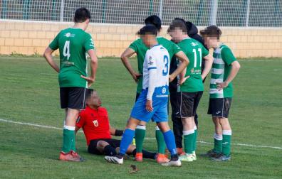 El árbitro, en el suelo con una herida en el labio, junto a jugadores de ambos equipos que se interesan por él