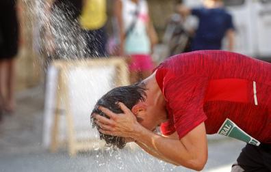 Un corredor, refrescándose durante una carrera popular en verano