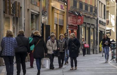 Varios grupos de personas pasean en la calle Zapatería, del Casco Viejo de Pamplona, con bolsas de compras.