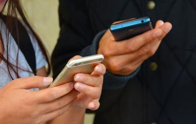 Dos personas consultan sus teléfonos móviles