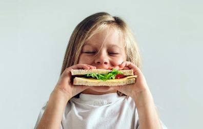 Una niña, comiendo un bocadillo
