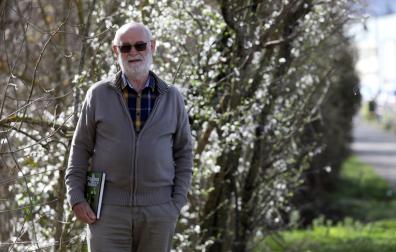 Cruz Miguel Babace posa en un paraje del paseo del Arga en el polígono de Landaben en Pamplona. Sostiene el libro de orquídeas silvestres de Navarra del que es coautor