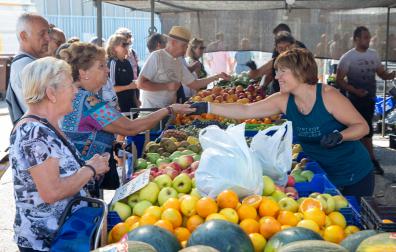 Varias personas compran en uno de los puestos de fruta y verdura del mercadillo de Landaben