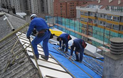 Varios trabajadores en una obra sobre un tejado