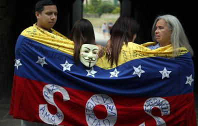 Ali Gómez, Eglee Torres y otras dos compatriotas, que prefieren no identificarse por temor a posibles represalias en su país, se envuelven en una bandera de hilo tejida en 2014 para manifestarse contra el régimen de Nicolás Maduro
