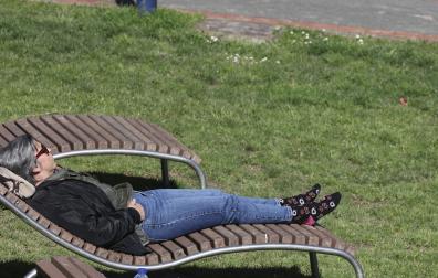 Una mujer toma el sol en un parque en el inicio de la primavera